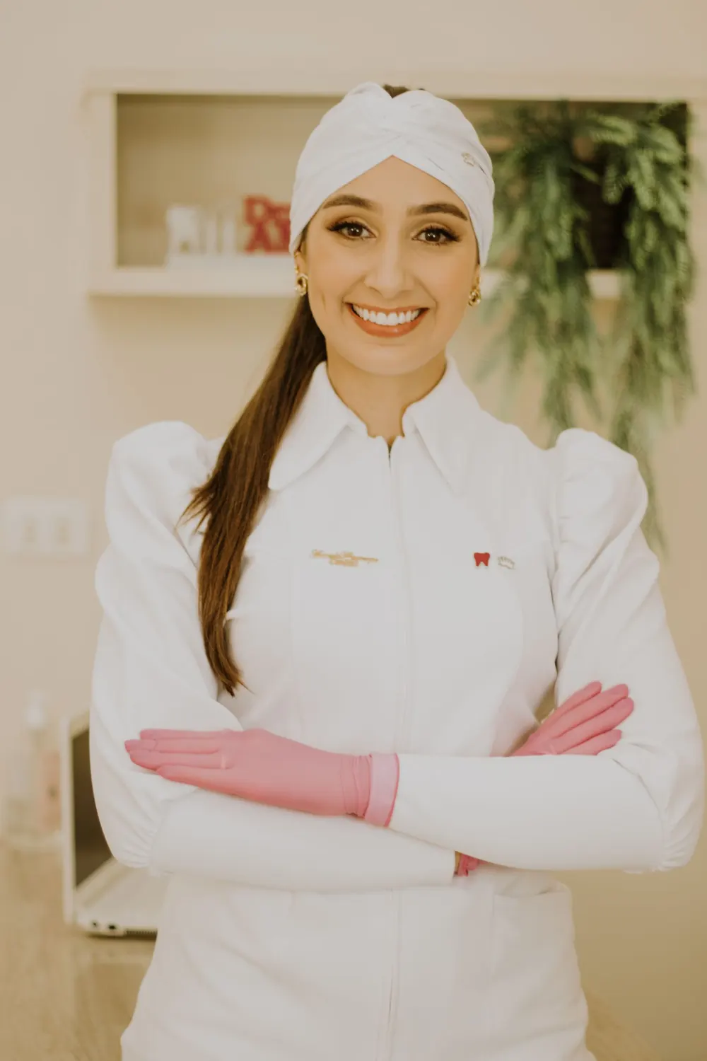 Uśmiechnięta lekarka dentystka w białym fartuchu i różowych rękawiczkach